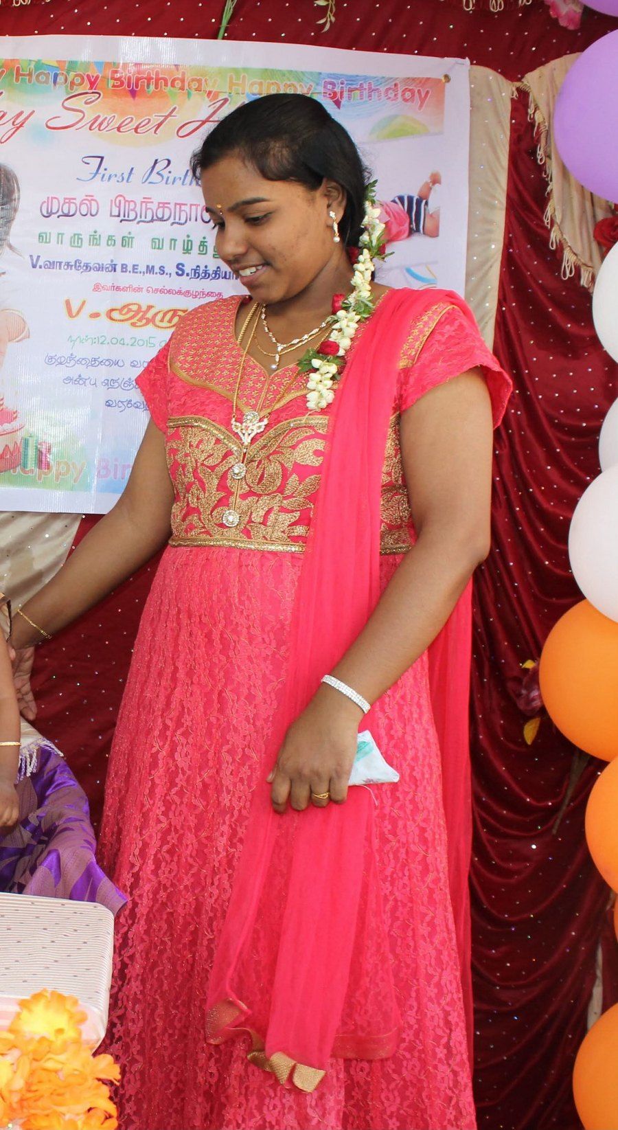 Nithya at the start of her journey, in a coral-pink embroidered dress at a family birthday celebration